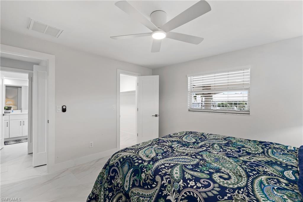 Bedroom featuring light marble finish flooring, a spacious closet, and a ceiling fan
