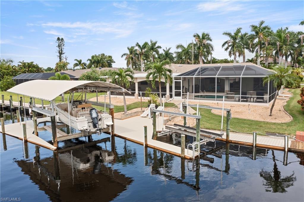 Dock area with boat lift, a water view, a sunroom, and glass enclosure