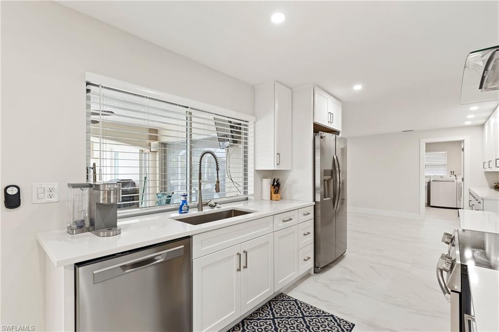 Kitchen with white cabinetry, appliances with stainless steel finishes, light marble finish flooring, recessed lighting, and light stone counters