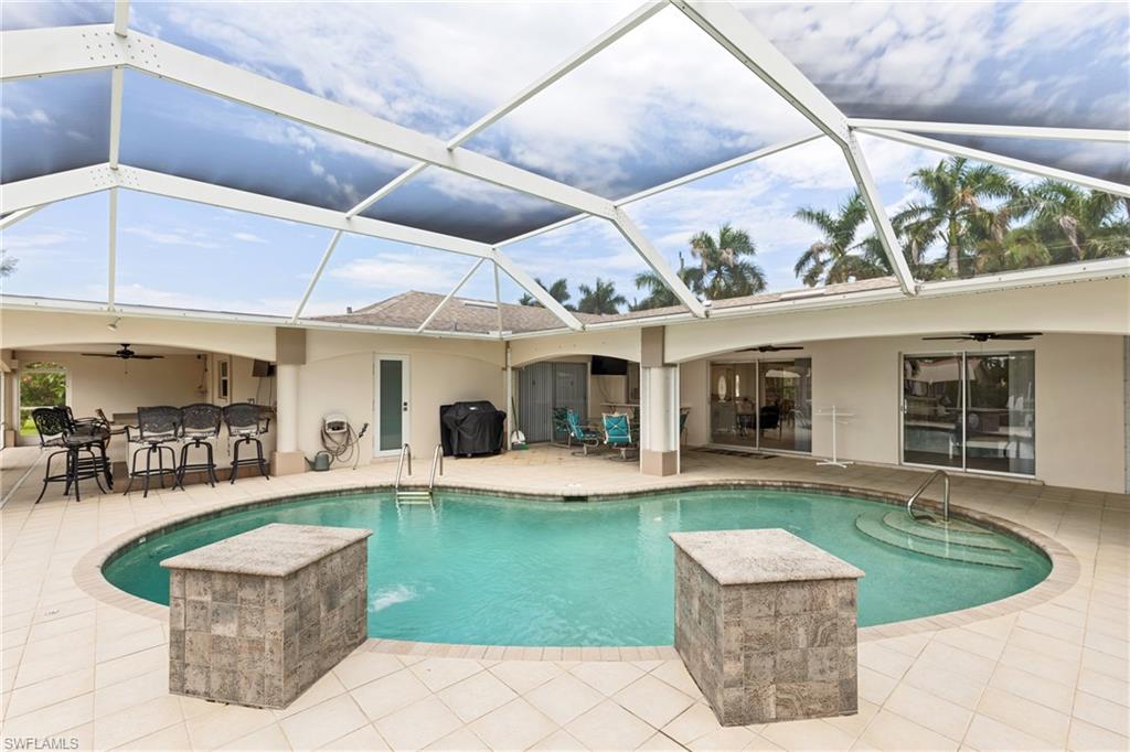 Swimming pool with a ceiling fan, a sunroom, grilling area, and a patio