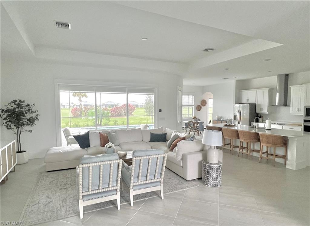 Living room featuring light tile patterned flooring, sink, and a tray ceiling