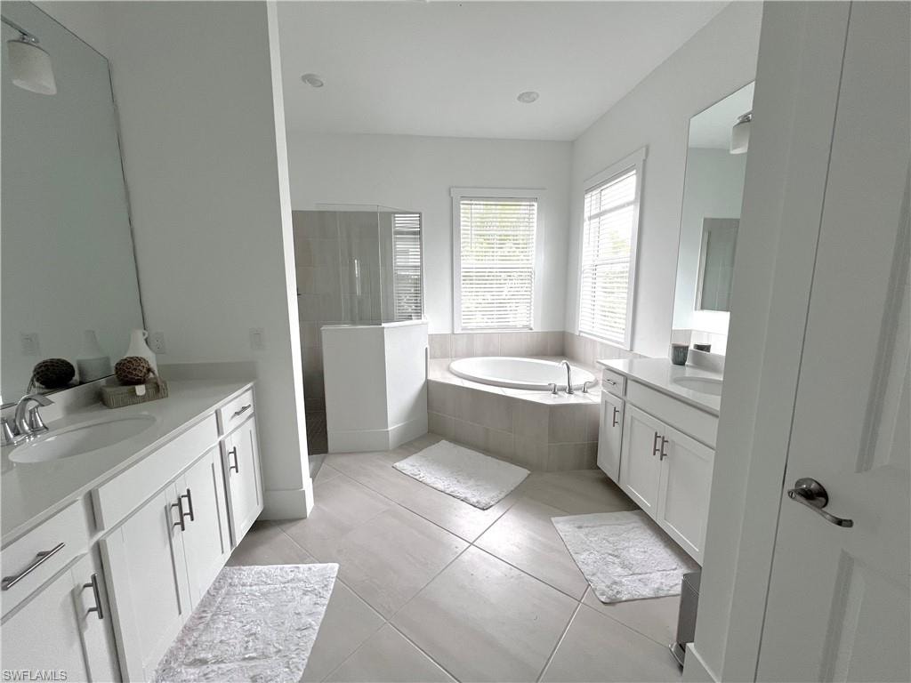 Bathroom featuring vanity, tiled tub, and tile patterned floors