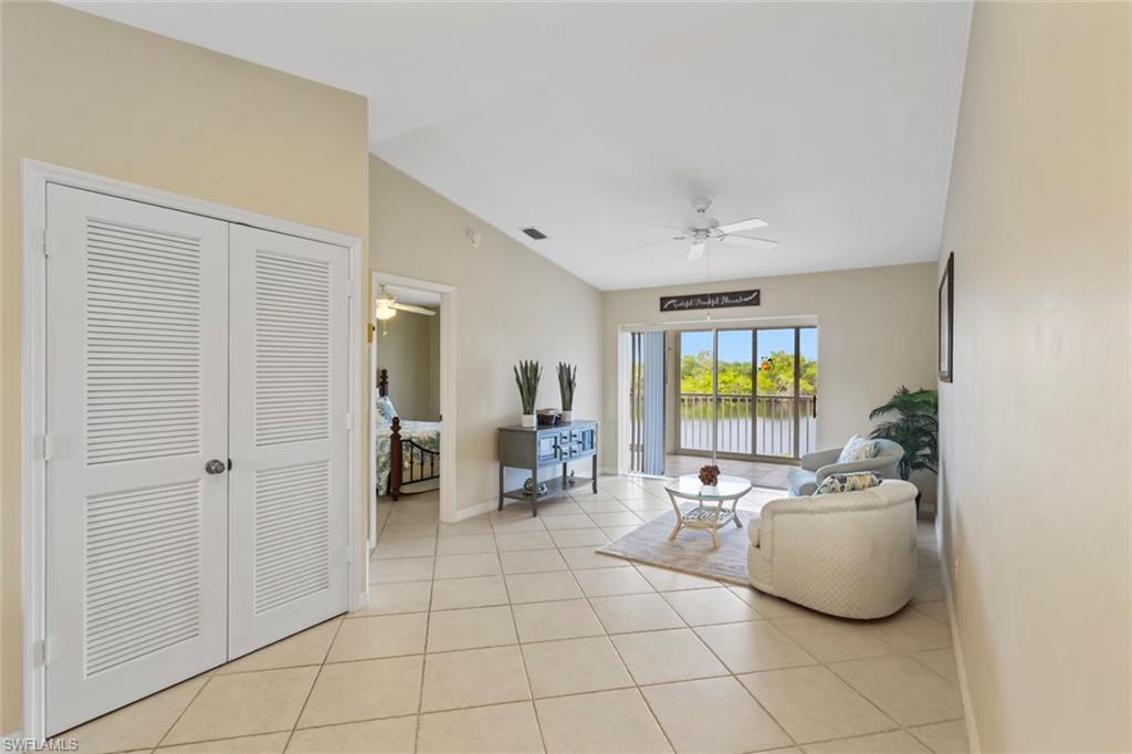Living room featuring lofted ceiling, light tile patterned floors, ceiling fan, and a water view