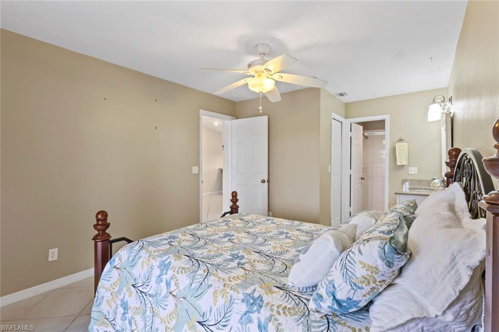Bedroom with tile patterned floors, a ceiling fan, and ensuite bath