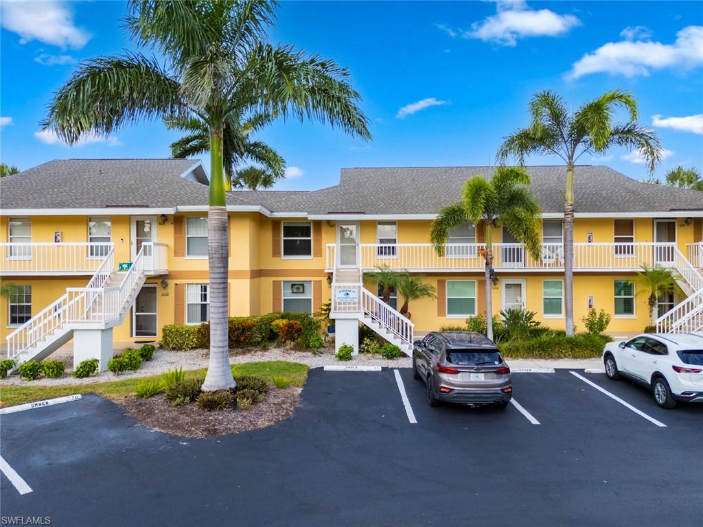 View of property featuring stairs and uncovered parking
