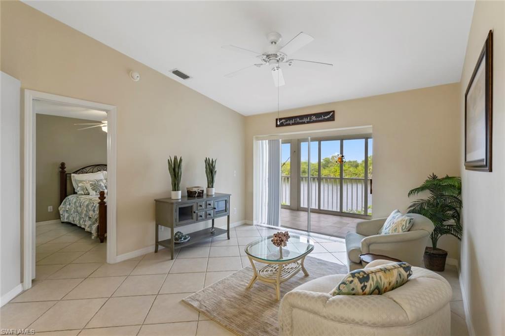 Living room with a ceiling fan, light tile patterned floors, and a water view