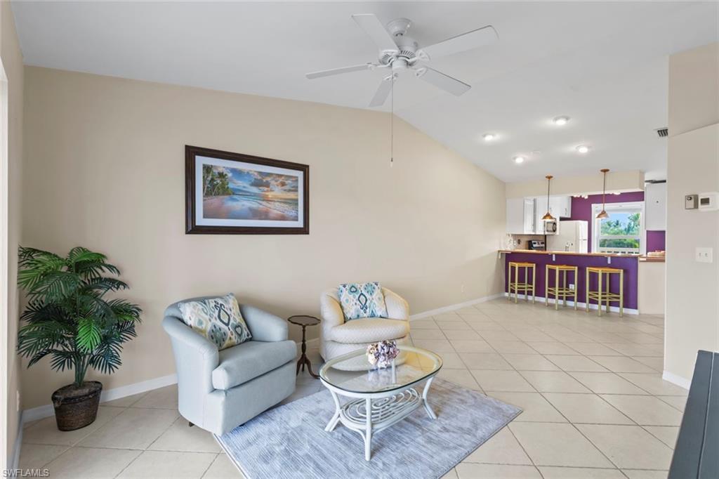 Living area with light tile patterned floors, lofted ceiling, and a ceiling fan
