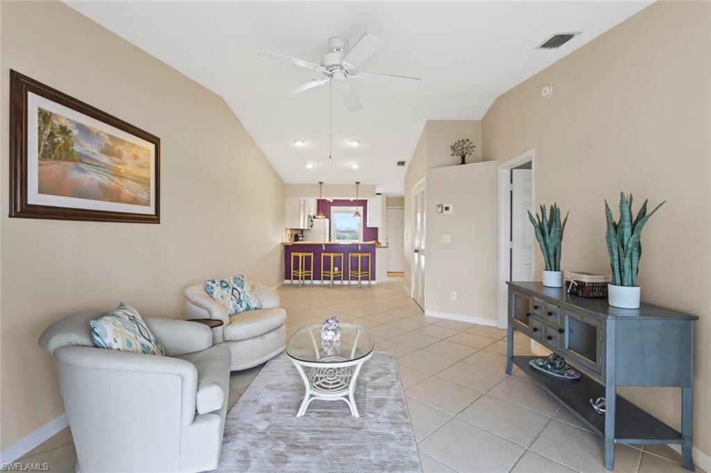Living room with light tile patterned floors, a ceiling fan, and vaulted ceiling