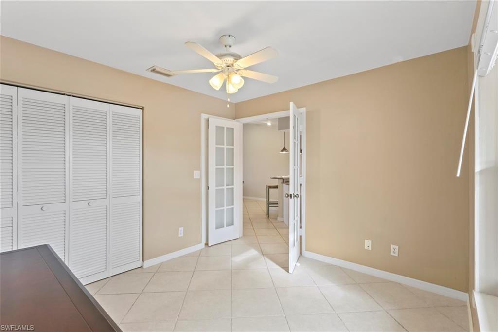 Unfurnished bedroom featuring light tile patterned floors, a ceiling fan, a closet, and french doors
