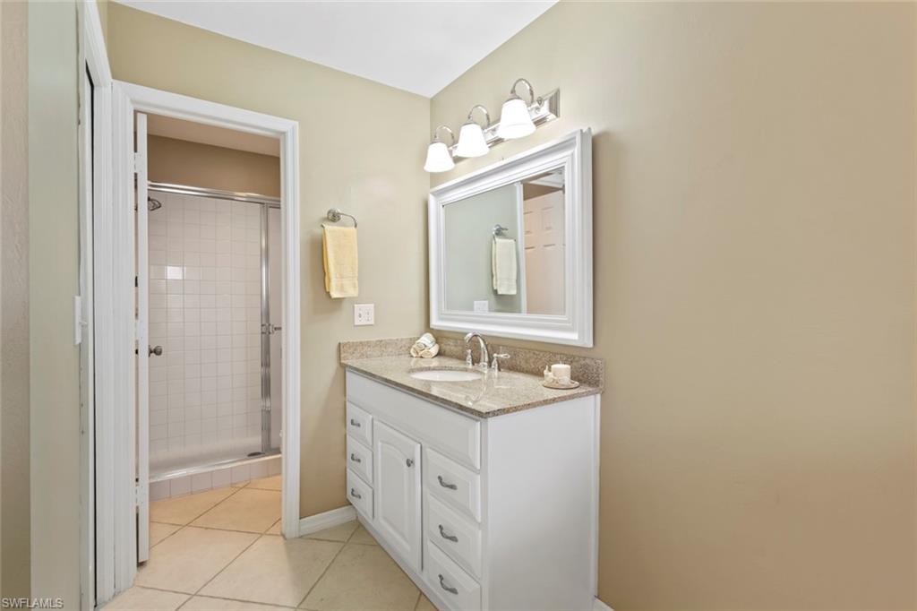 Bathroom featuring vanity, light tile patterned floors, and a shower stall