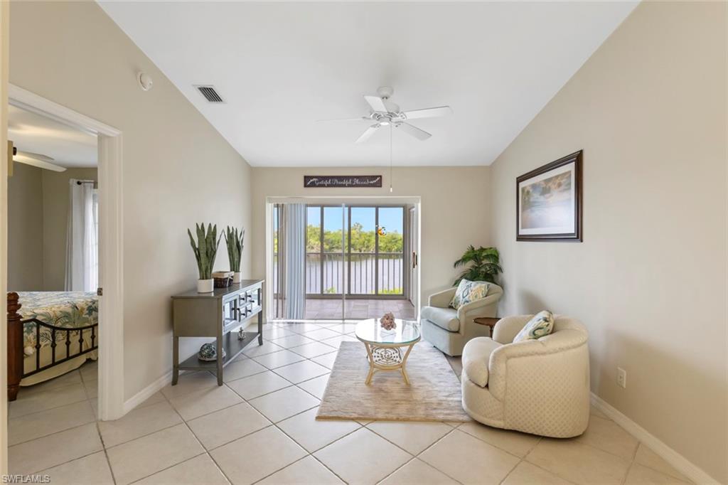 Living area featuring a ceiling fan, light tile patterned floors, and a water view