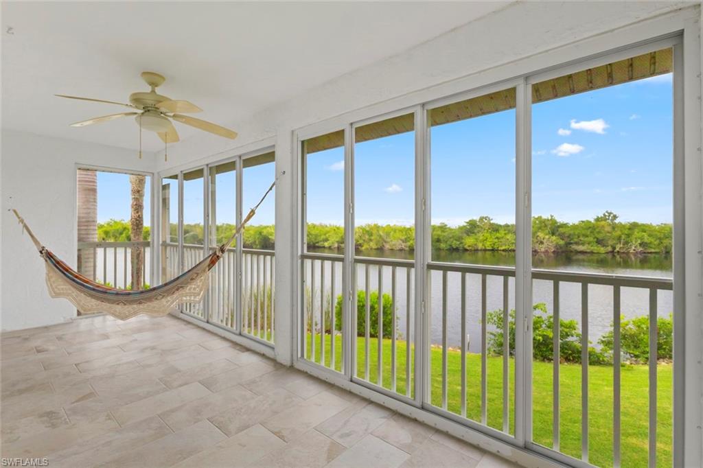Unfurnished sunroom with a water view and view of wooded area