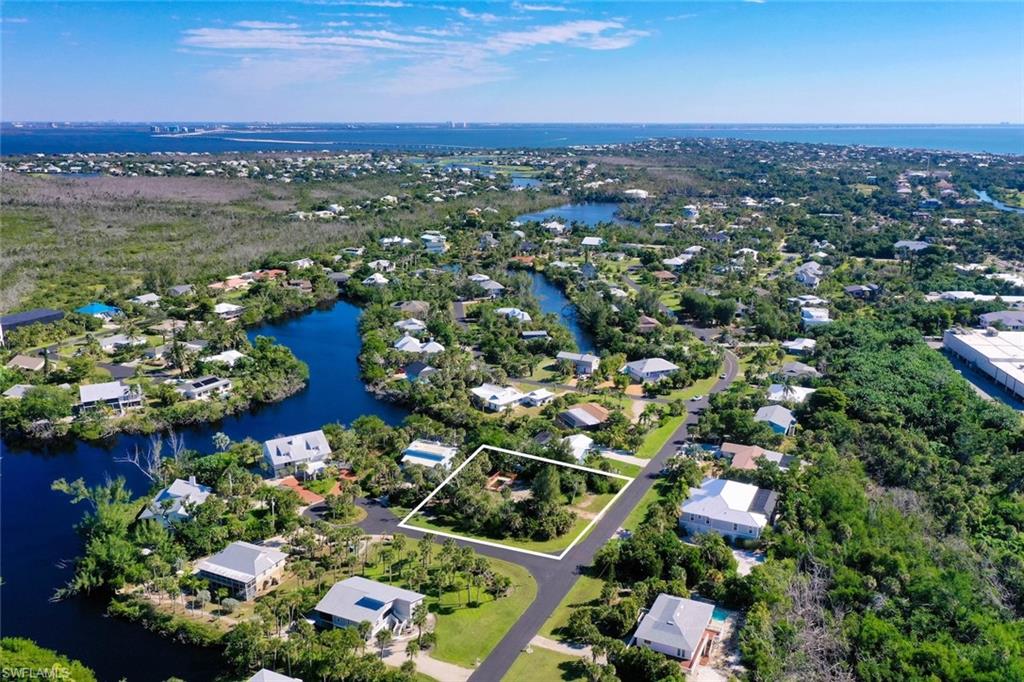 Aerial perspective of suburban area featuring a large body of water and property boundaries highlighted