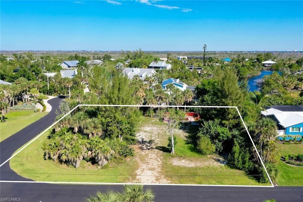 Aerial perspective of suburban area with property parcel outlined and a tree filled landscape