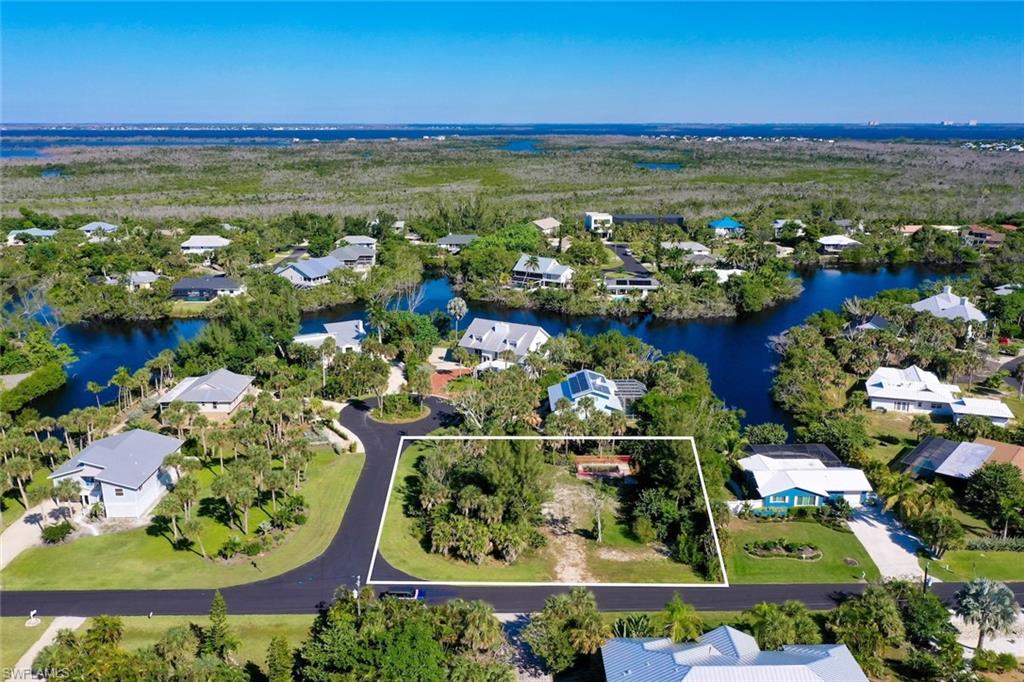 Aerial view of residential area with property parcel outlined and a nearby body of water