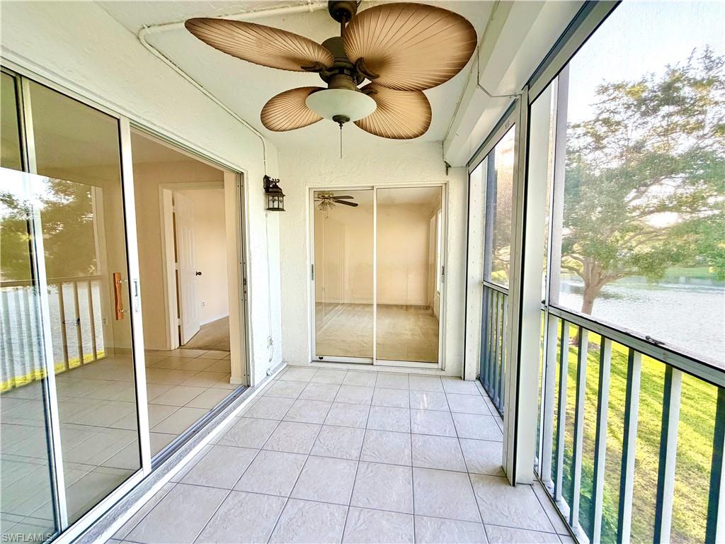 Screened-in balcony featuring square tile flooring and a ceiling fan with light fixture