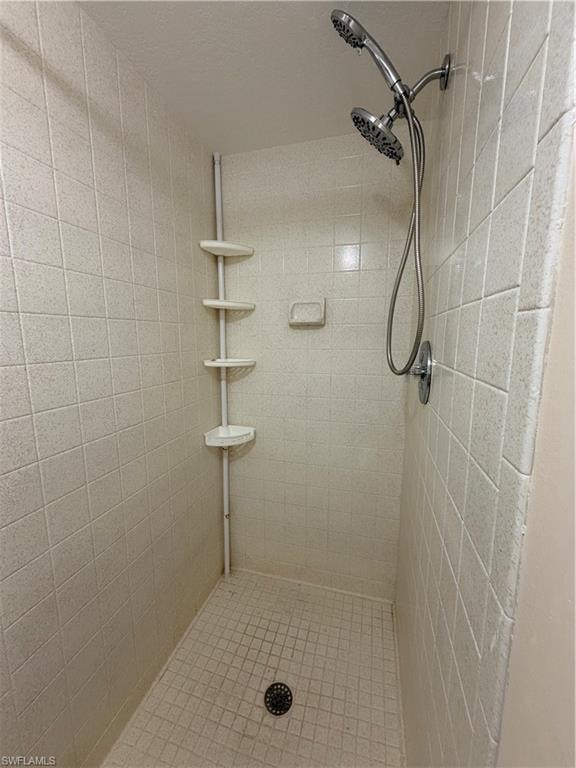 Walk-in shower with light-colored square wall tiles and smaller mosaic floor tiles