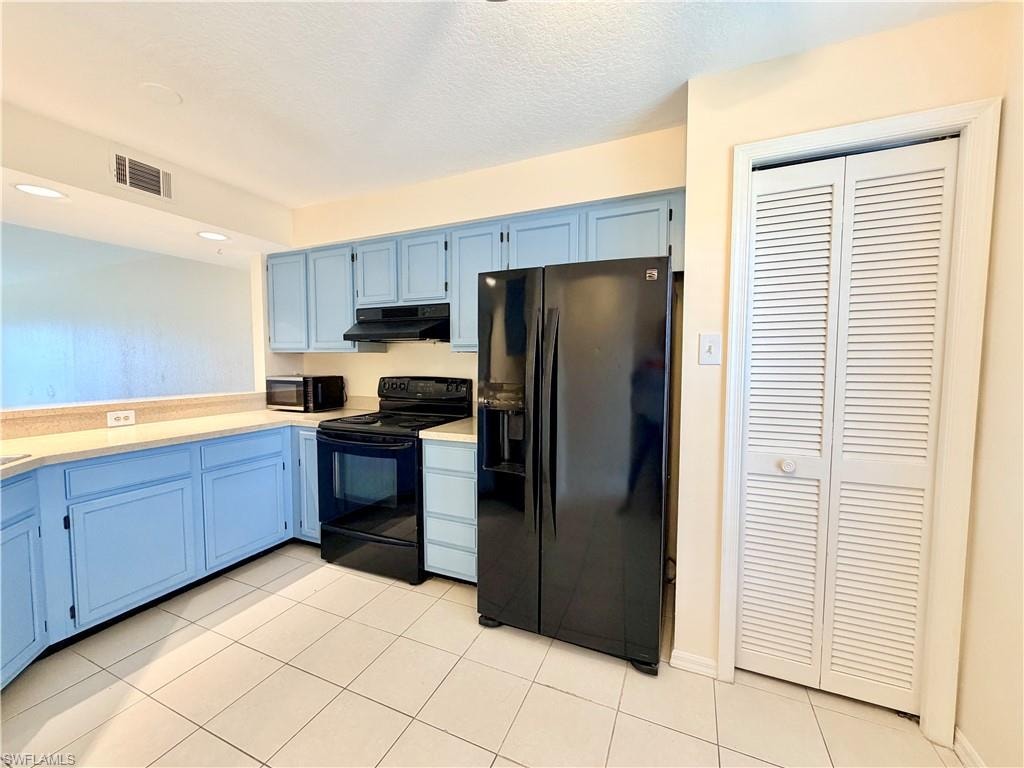 Kitchen featuring light blue cabinetry, light-colored countertops, and white tile flooring
