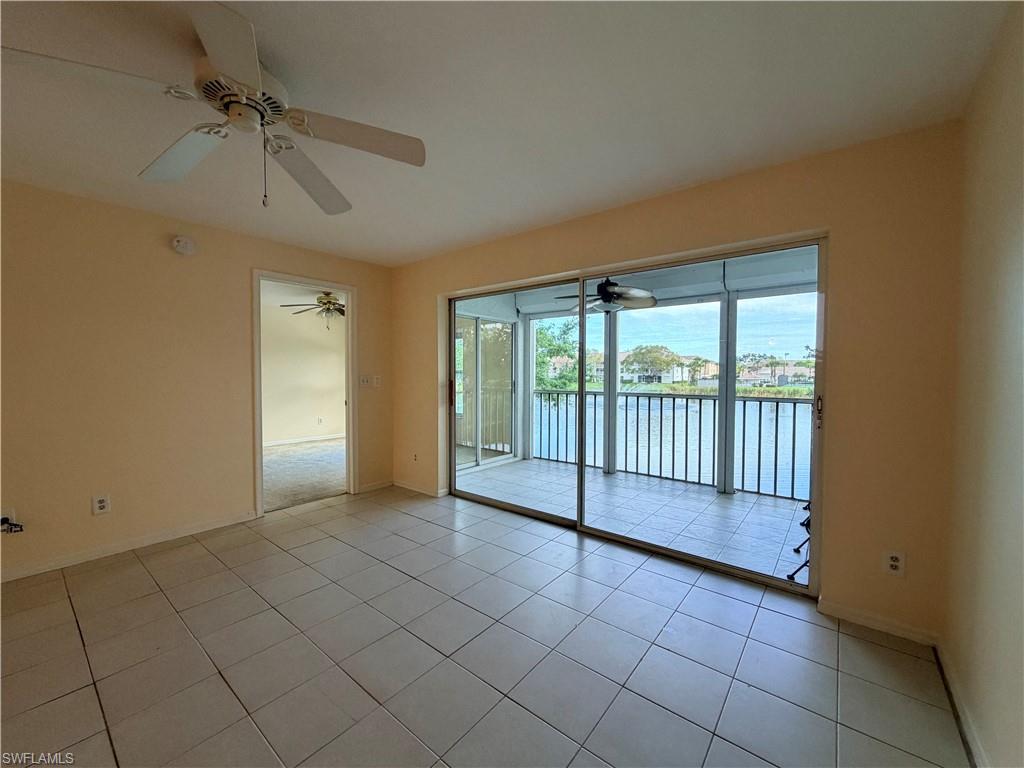 Spacious room featuring neutral-toned walls, tile flooring, and a ceiling fan