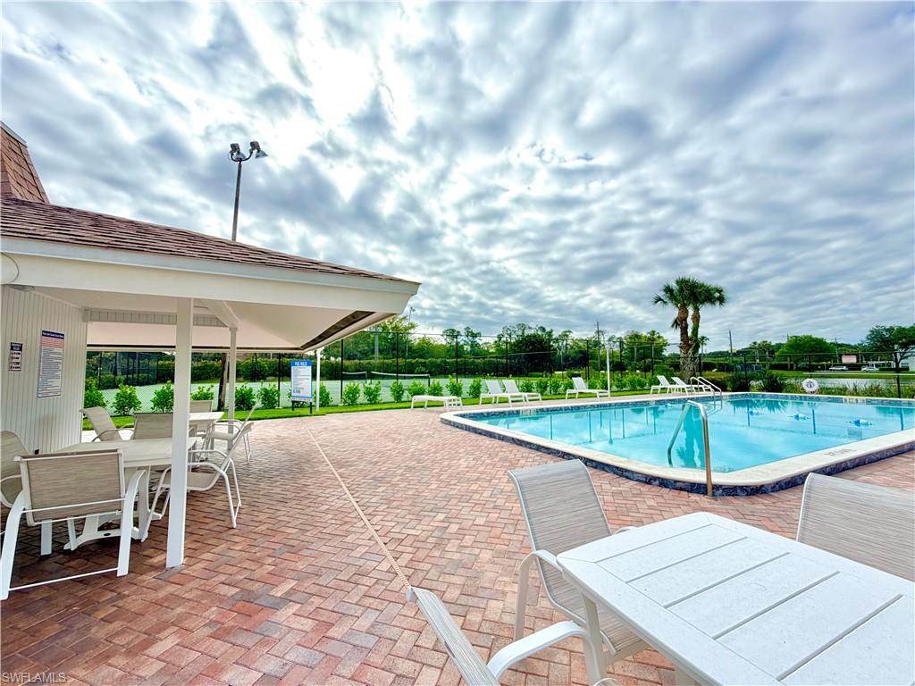 Community pool featuring a paver deck, covered patio, and perimeter fencing