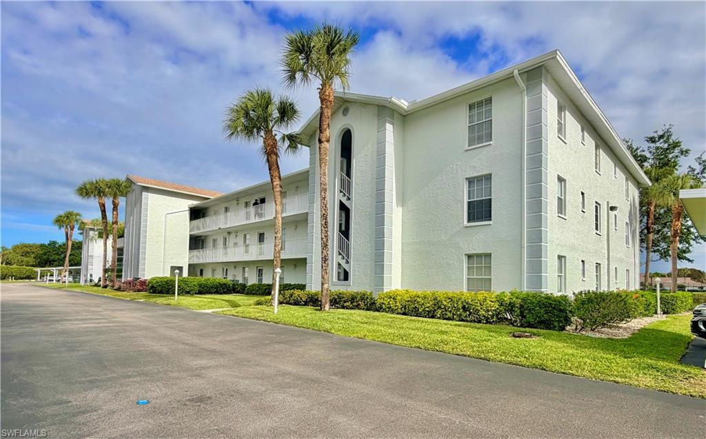 Multi-level residential building featuring stucco exterior, multiple private balconies, and mature palm trees