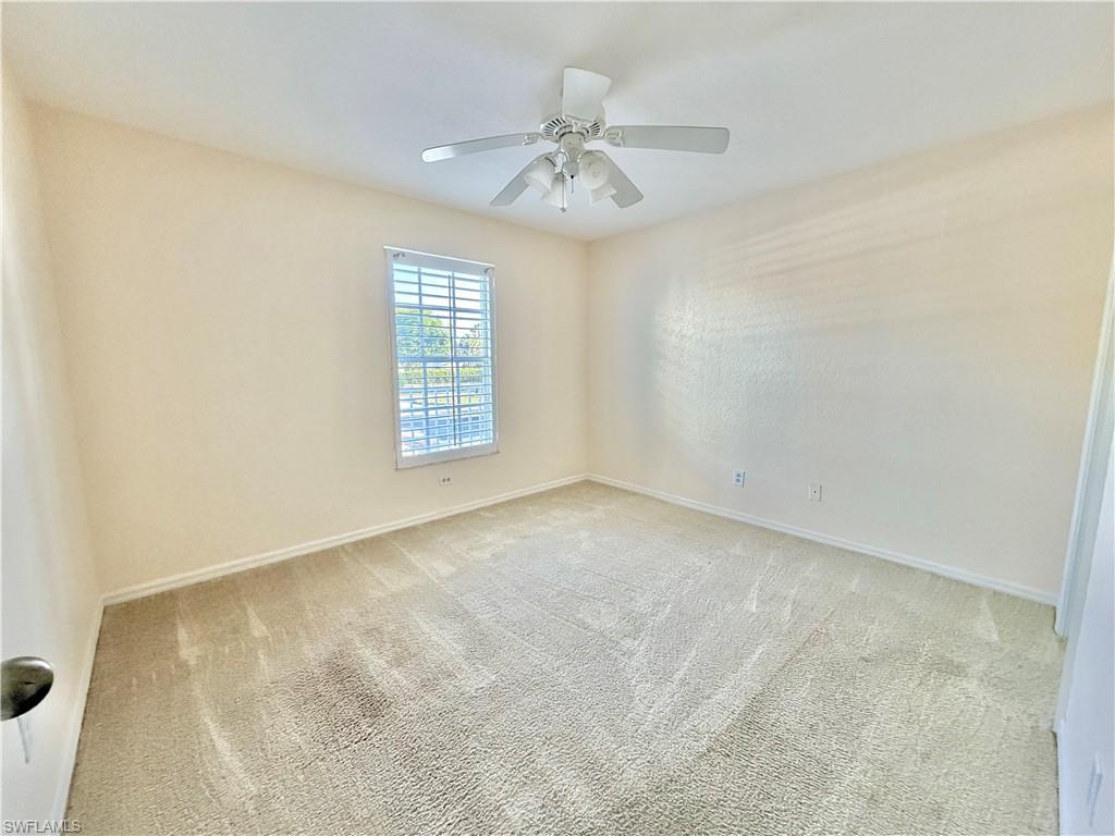 guest bedroom featuring neutral carpeting, a ceiling fan with integrated lighting, and a window with plantation shutters