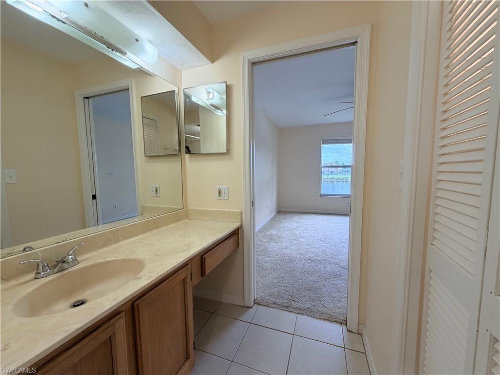 Bathroom vanity featuring a single basin sink, light-toned countertop, and wood-finish cabinetry