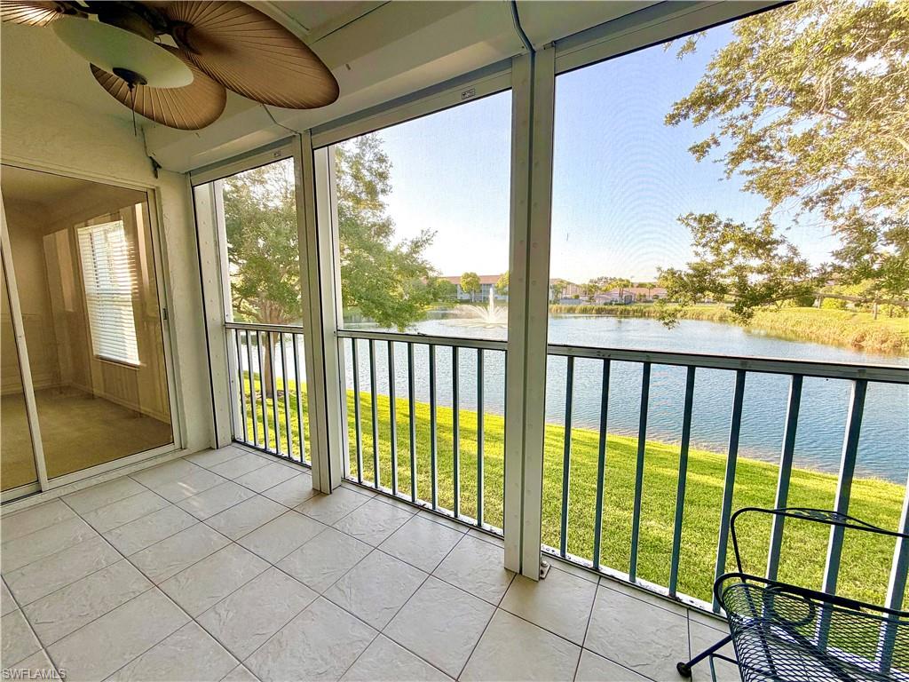 Screened balcony featuring expansive water frontage, a distant water fountain, and mature landscaping