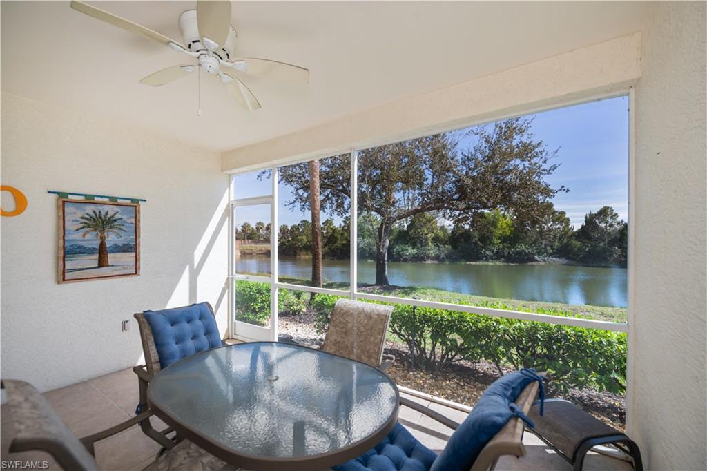 Sunroom with a textured wall, a water view, and view of scattered trees