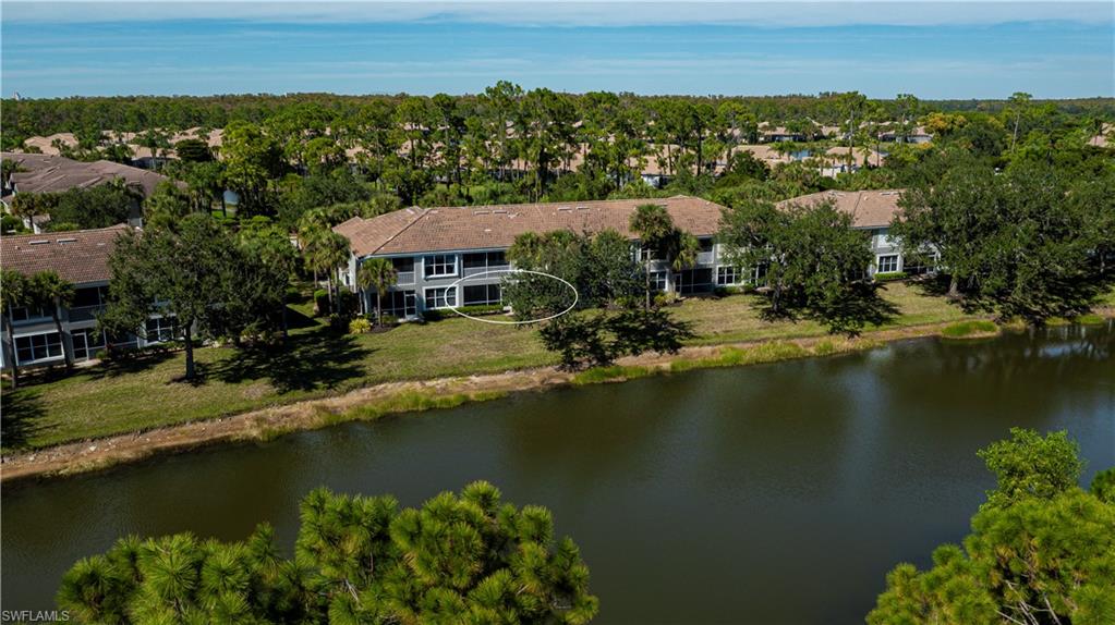Aerial view of residential area with a nearby body of water and a tree filled landscape