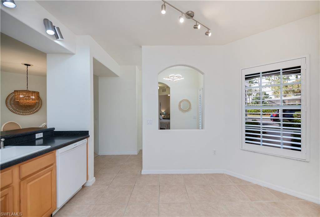Kitchen featuring white dishwasher, light tile patterned floors, arched walkways, and pendant lighting