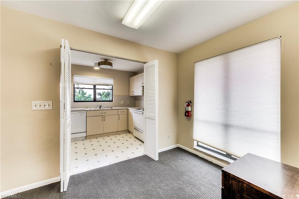 Kitchen with light countertops, light colored carpet, white appliances, and cream cabinets