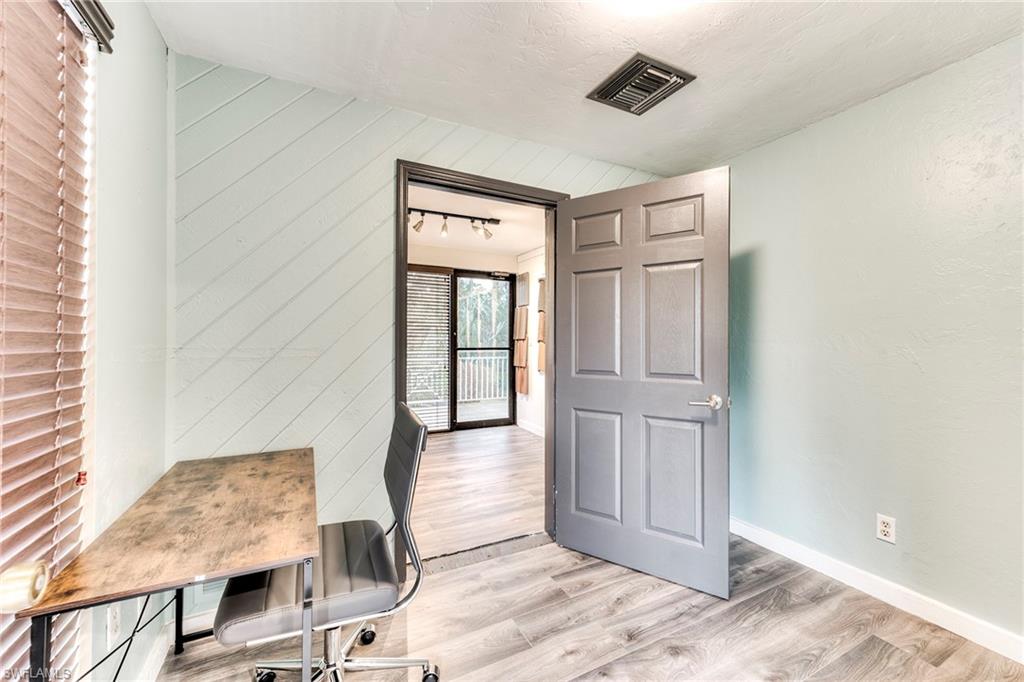 Home office featuring light wood-type flooring, wooden walls, and a textured ceiling