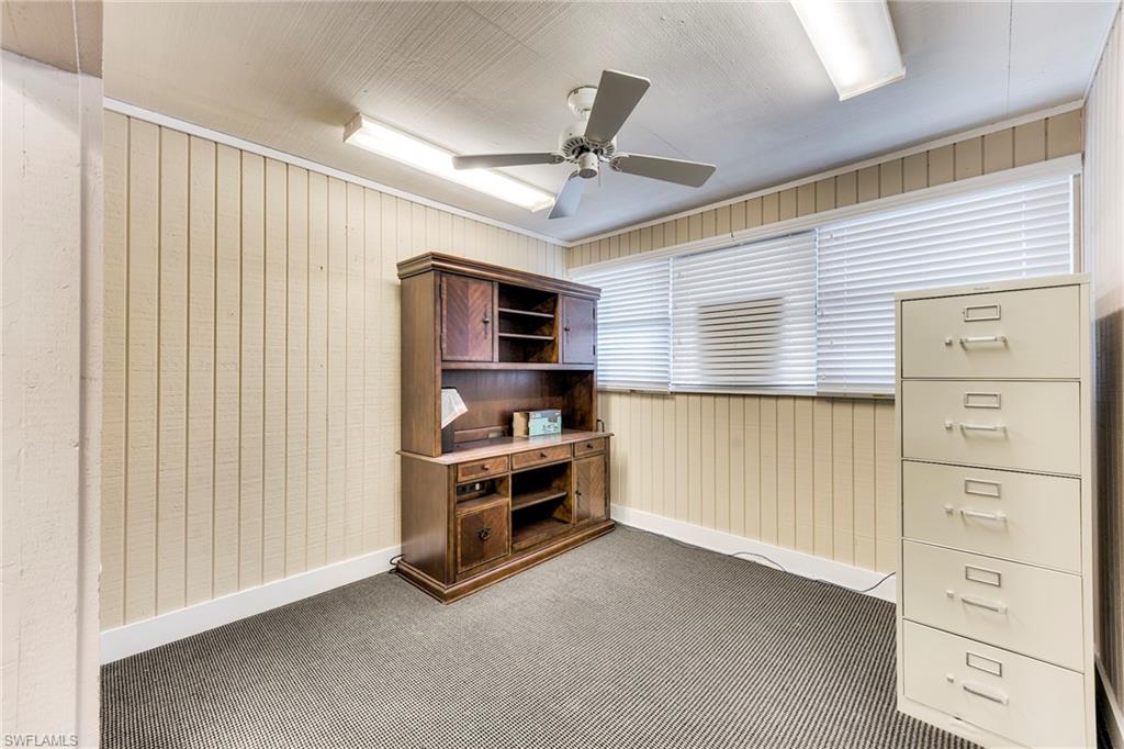 Unfurnished office featuring wooden walls, carpet flooring, and ceiling fan