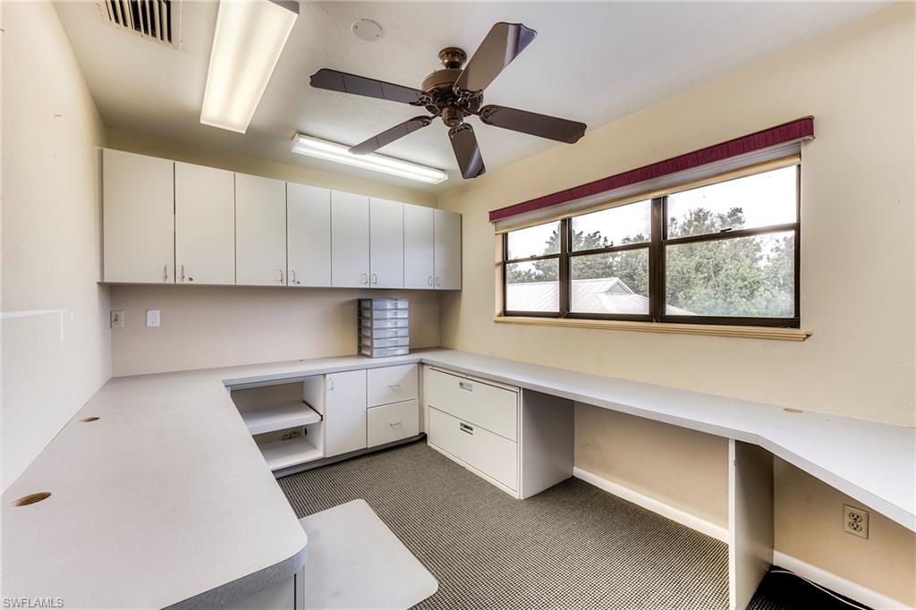 Unfurnished office with a ceiling fan, built in study area, and dark carpet