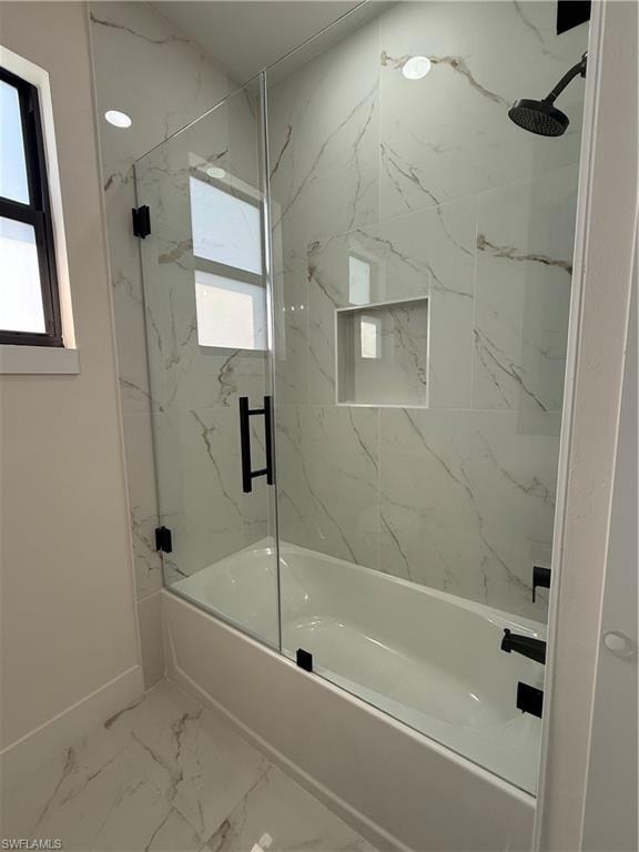 Full bathroom featuring combined bath / shower with glass door and light marble finish flooring