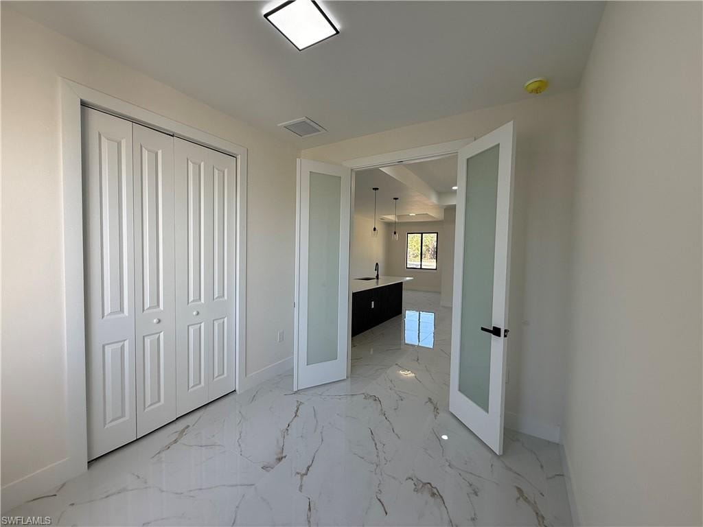 Unfurnished bedroom with light marble finish flooring and a closet