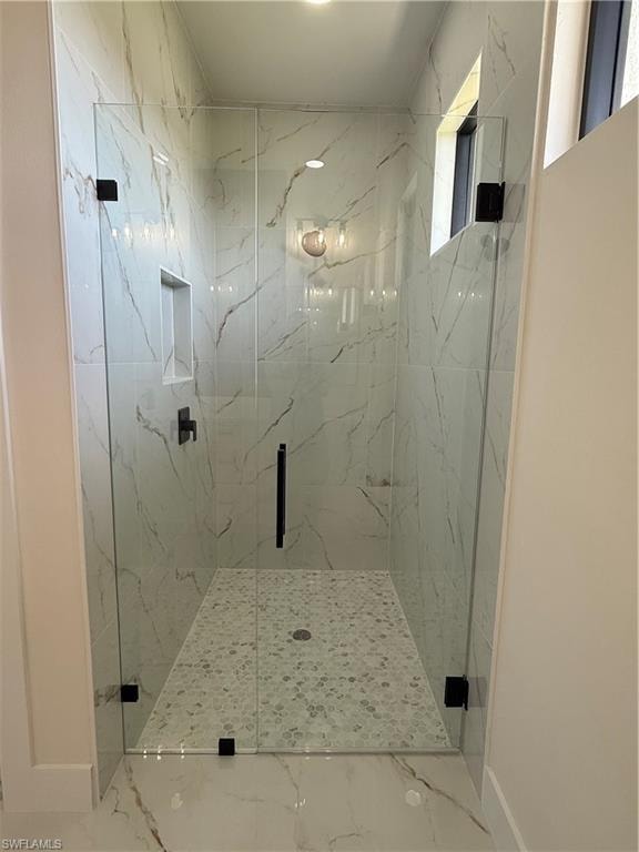 Full bathroom with a marble finish shower and baseboards