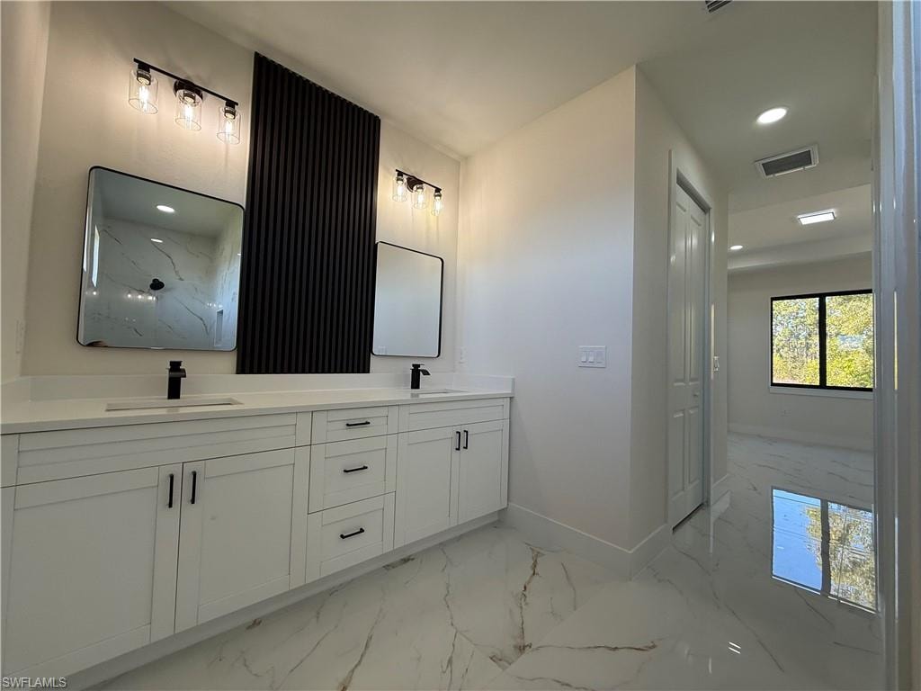Full bath with double vanity, recessed lighting, and light marble finish flooring