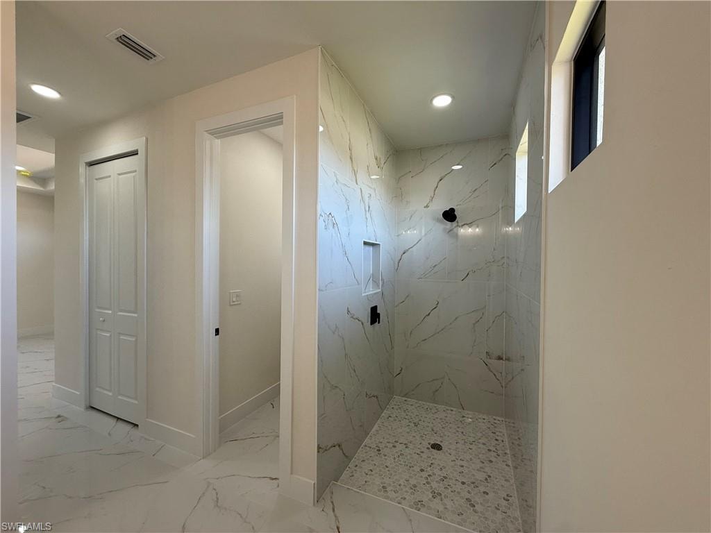 Full bath with a marble finish shower, recessed lighting, light marble finish floors, and a closet