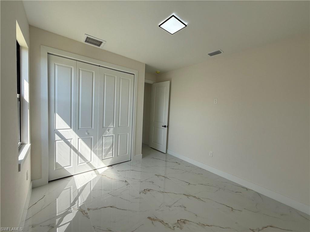 Unfurnished bedroom featuring light marble finish flooring and a closet