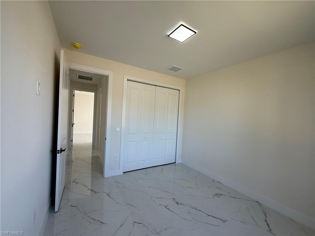 Unfurnished bedroom featuring light marble finish floors and a closet