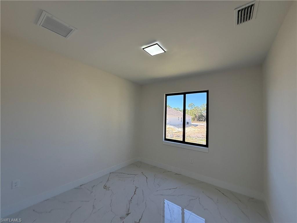 Unfurnished room featuring baseboards and light marble finish flooring
