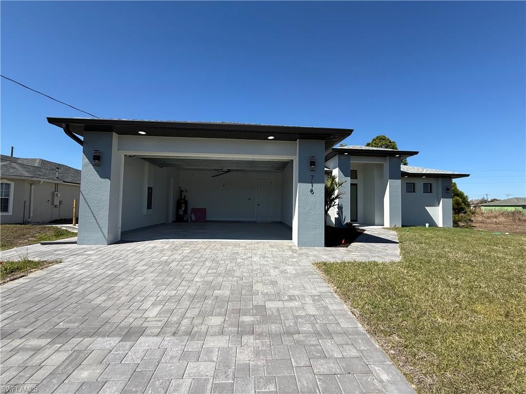 View of front of property with a front lawn, decorative driveway, and stucco siding