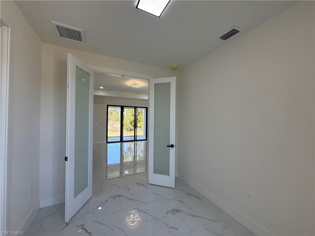 Unfurnished room featuring french doors and light marble finish floors
