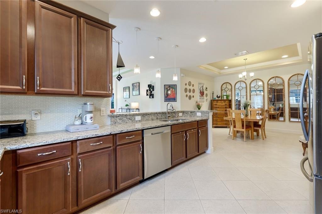 Living area featuring a tray ceiling, light tile patterned floors, recessed lighting, and ceiling fan