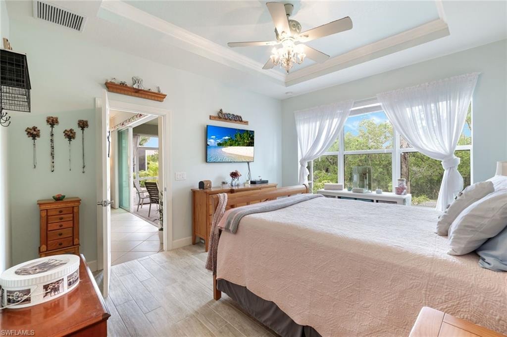 Bedroom featuring a tray ceiling, light wood finished floors, and a ceiling fan
