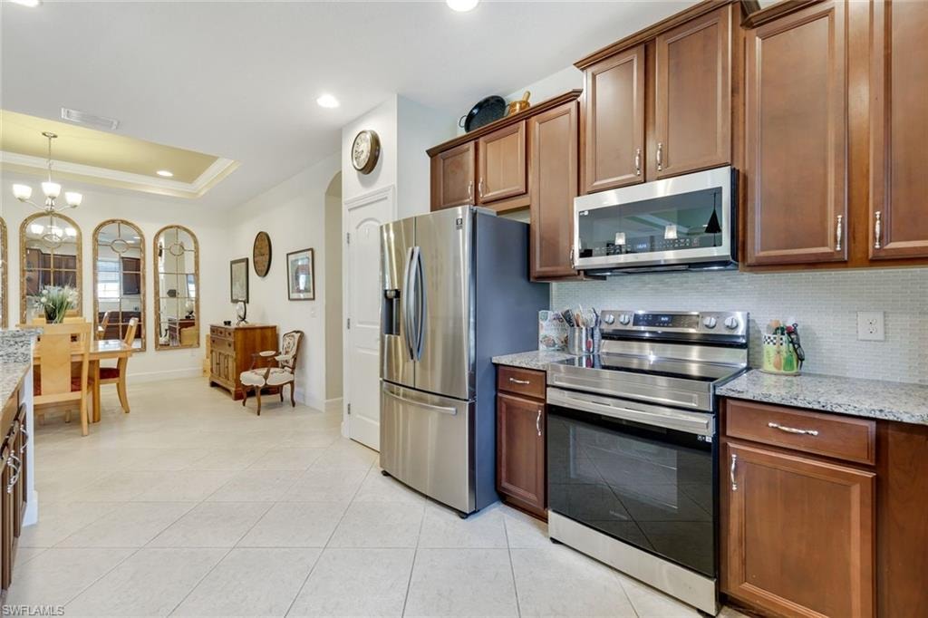 Kitchen featuring backsplash, stainless steel appliances, light stone countertops, light tile patterned flooring, and recessed lighting
