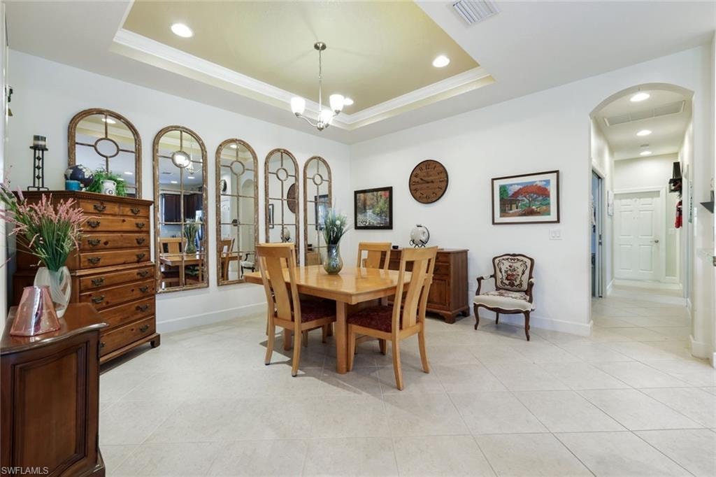 Kitchen with a breakfast bar, arched walkways, light tile patterned flooring, pendant lighting, and light stone counters