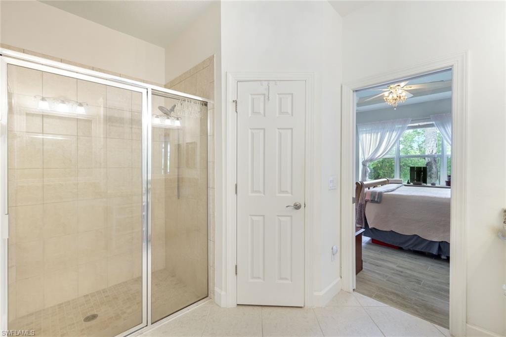 Full bathroom featuring a stall shower, a chandelier, light tile patterned floors, vanity, and a closet